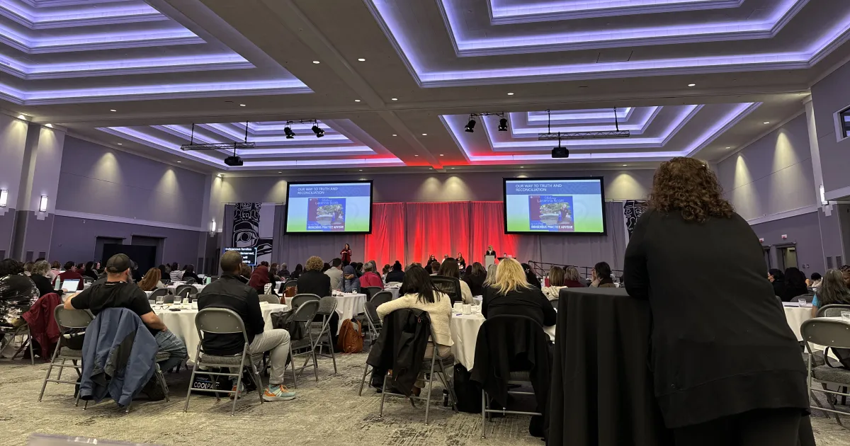 A large conference hall looking towards the stage from the back of the room. 